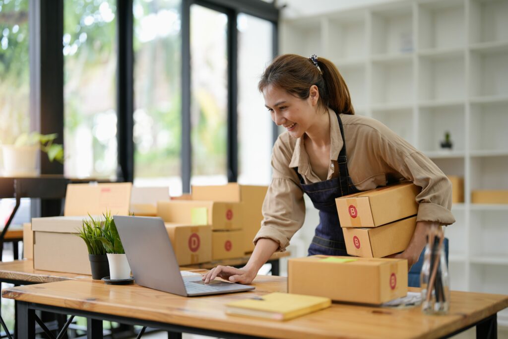 How to sell online: SME entrepreneur Small business entrepreneurs Online selling ideas,Happy Young Asian business owner work on computer and a boxs at home,delivery SME procurement package box deliver to customers,