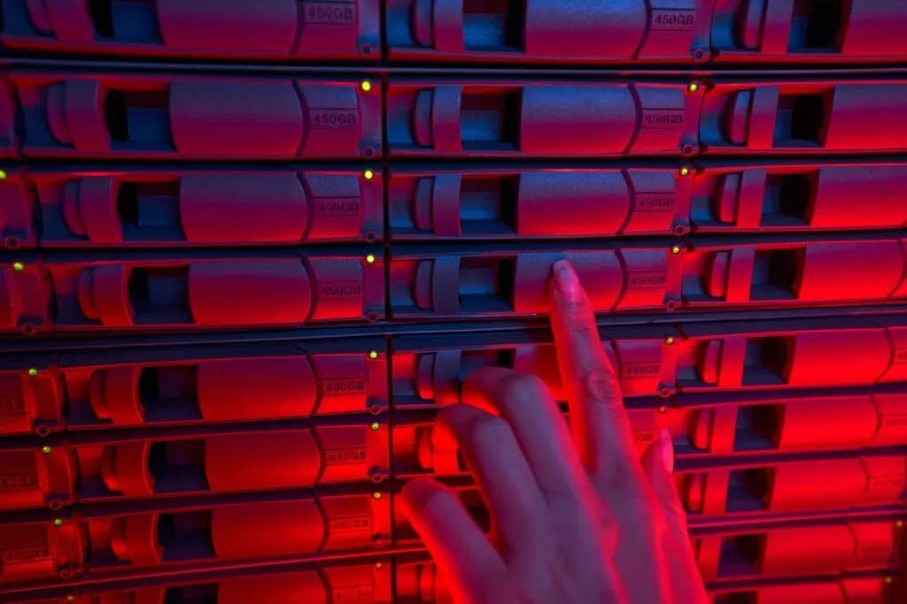 choose a web host: Cropped view of female system administrator checking hard drive at enterprise datacenter, red color toned image